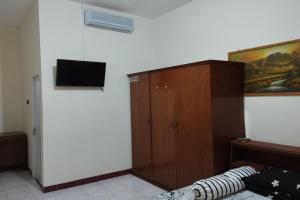 1 dormitorio con 1 cama, TV y armario en OYO 92756 Kos Moncok en Tjakranegara