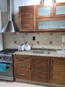 uma cozinha com armários de madeira, um lavatório e um fogão em Casona centrica alameda Mendoza em Mendoza