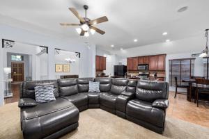 a living room with a leather couch and a kitchen at Parkside Serenity Bear Creek and Sam Race Track in Houston