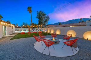 a group of red chairs sitting on a patio at Acacia Retreat by Rather Be Properties in Palm Springs