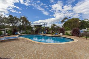 Una piscina en un patio con sillas y un cielo en NRMA Eastern Beach Holiday Park, en Lakes Entrance