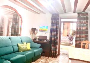 ein Wohnzimmer mit einem blauen Sofa und einem Klavier in der Unterkunft Casa El Cerro in Villacarrillo