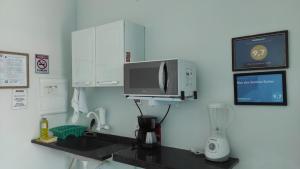 a kitchen with a coffee maker and a microwave at Mar dos Sonhos Suítes in Ubatuba