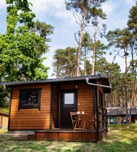 eine Hütte im Wald mit einem Tisch auf der Veranda in der Unterkunft Osada Lubniewice - Domki letniskowe nad samym jeziorem na wynajem 2-8osób in Lubniewice