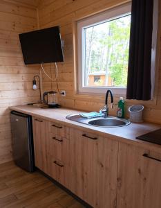 a kitchen with a sink and a window in a cabin at Osada Lubniewice - Domki letniskowe nad samym jeziorem na wynajem 2-8osób in Lubniewice