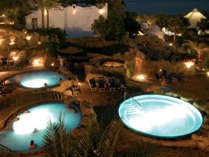 two swimming pools at night with chairs and lights at Appartamento Elisir Domina Coral Bay in Sharm El Sheikh