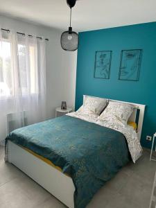 una camera da letto con un letto con una parete blu di Vacances en Ardèche "maison pont d'arc" a Vallon-Pont-dʼArc