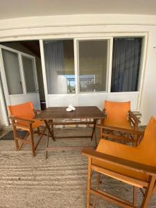 a wooden table and chairs in a room with a window at Yellow Beach House in Logaras