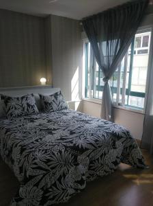 Una cama con una manta blanca y negra y una ventana en Estudio. Sada, A Coruña., en Sada