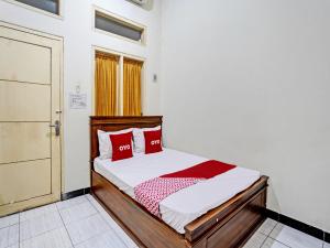 ein Schlafzimmer mit einem Bett mit roten Kissen und einer Tür in der Unterkunft OYO Life 92773 Griya Trubus Syariah in Tuban