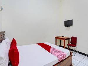 Schlafzimmer mit einem Bett, einem Schreibtisch und einem TV in der Unterkunft OYO Life 92773 Griya Trubus Syariah in Tuban