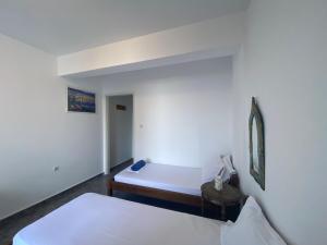 a white room with two beds and a mirror at Mini Beach House in Logaras