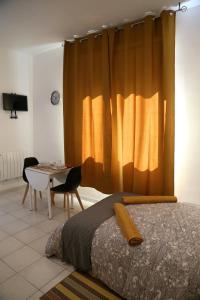 ein Schlafzimmer mit einem Bett, einem Tisch und einem Vorhang in der Unterkunft MERCURE in Saint-Quentin
