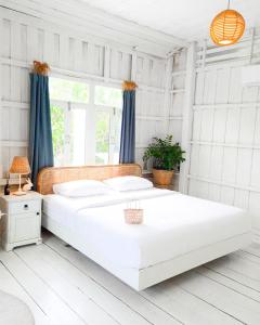 - une chambre blanche avec un grand lit blanc et une fenêtre dans l'établissement One Chan Farmstay, à Chanthaburi