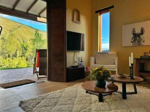 a living room with a tv and a couch and a table at Casita Icatá con vista a la montaña (A 5 minutos del pueblo) in Villa de Leyva