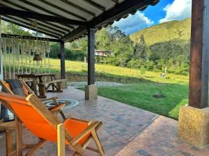 d'une terrasse avec une table et des chaises et une vue sur un champ. dans l'établissement Casita Icatá con vista a la montaña (A 5 minutos del pueblo), à Villa de Leyva