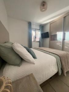 Un dormitorio con una cama grande con almohadas verdes y blancas en Apartamento Kai, en Playa de Jandía