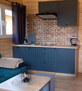 a kitchen with blue cabinets and a brick wall at Osada Lubniewice - Domki letniskowe nad samym jeziorem na wynajem 2-8osób in Lubniewice