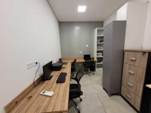 una oficina con 2 escritorios y sillas en una habitación en Quarto Zen, en São Paulo