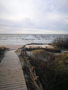 un paseo marítimo que conduce a una playa con el océano en Dobilas ir jura, en Palanga