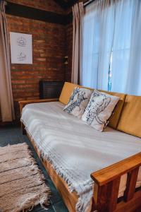 una cama de madera con almohadas frente a una ventana en Casa cálida en Esquel en Esquel