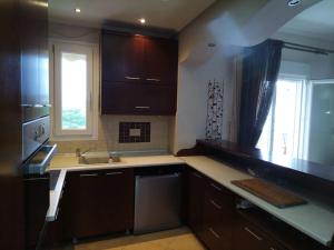 eine Küche mit braunen Schränken, einem Waschbecken und einem Fenster in der Unterkunft Vasiliki's Apartment in Nea Kallikratia