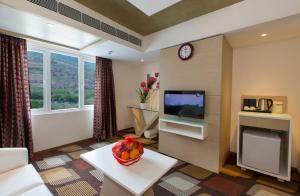 a living room with a television and a bowl of fruit on a table at Pai Viceroy in Tirupati