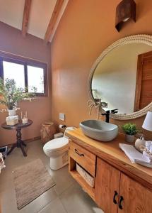 een badkamer met een wastafel, een toilet en een spiegel bij Casa Araní - Vista espectacular y mucho jardín in Villa de Leyva