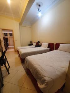 a room with three beds in a room at Hotel Achark in Bou Arfa