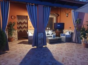 ein Wohnzimmer mit blauen Vorhängen und einem TV in der Unterkunft Casa El Albero (Torcal-Caminito del Rey) in La Joya