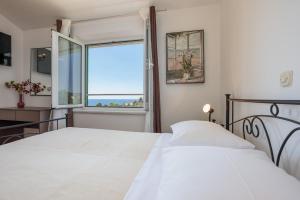 1 dormitorio con 2 camas blancas y ventana en Apartments Delfin, en Krk