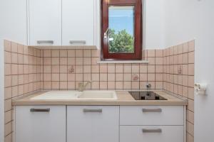 a white kitchen with a sink and a window at Apartments Delfin in Krk