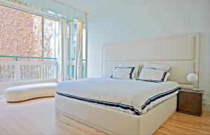 biała sypialnia z łóżkiem i dużym oknem w obiekcie Avenue Montaigne - Prestigieux 2BR w Paryżu