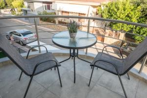 a glass table and two chairs on a balcony at Vonitsa Luxury Apartments in Vonitsa