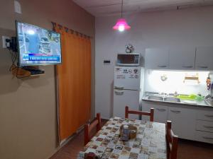 a small kitchen with a table and a tv on the wall at Linda vista in Arroyo de Los Patos