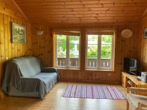 a living room with a chair and a tv and windows at Golden Seaside Villa in Kärdla