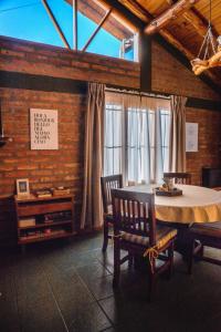 comedor con mesa, sillas y ventanas en Casa cálida en Esquel en Esquel