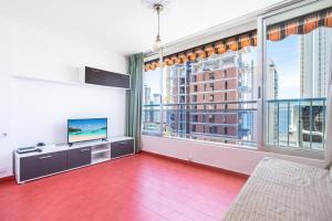 a living room with a large window and a tv at Ducado 10-J Apartment Levante Beach in Benidorm
