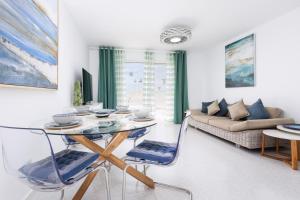 a living room with a glass table and blue chairs at Casa Birke in Costa Calma