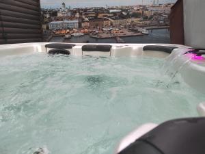 a jacuzzi tub with a view of a city at Private apartment suite with sauna themed bedroom, private jacuzzi, city center by train 15min in Helsinki