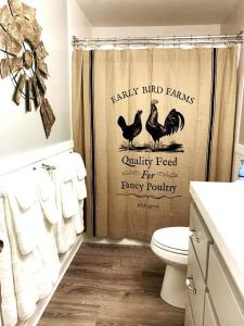 a bathroom with a shower curtain with chickens on it at Mae’s Cottage in the Clouds in Blue Ridge
