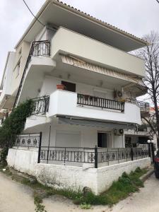 a white house with balconies and a fence at Andres house in Polychrono