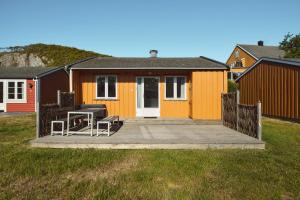 a yellow house with a deck with a table and chairs at Hvasser Motell in Hvasser