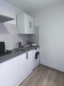 uma cozinha branca com uma máquina de lavar roupa e um lavatório em Cantarranas em Requena