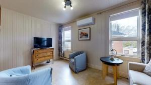 uma sala de estar com uma televisão, um sofá e uma mesa em Manoir Belle Plage em Carleton-sur-Mer
