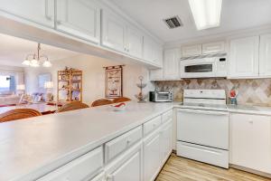 una cocina con armarios blancos y electrodomésticos blancos en Atlantic Ocean View Condo en Fernandina Beach