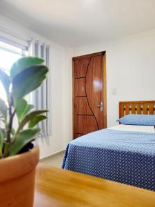 1 dormitorio con cama azul y puerta de madera en Praieira Hostel&Pousada, en Itacaré