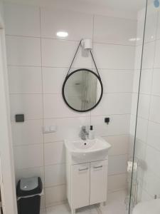 a white bathroom with a sink and a mirror at Apartament 592 in Boguszów-Gorce