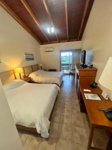 a hotel room with two beds and a desk and a television at Hotel Maitei Posadas in Posadas