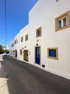 a white building with blue doors on a street at Valente Rooms Kythira in Kythira